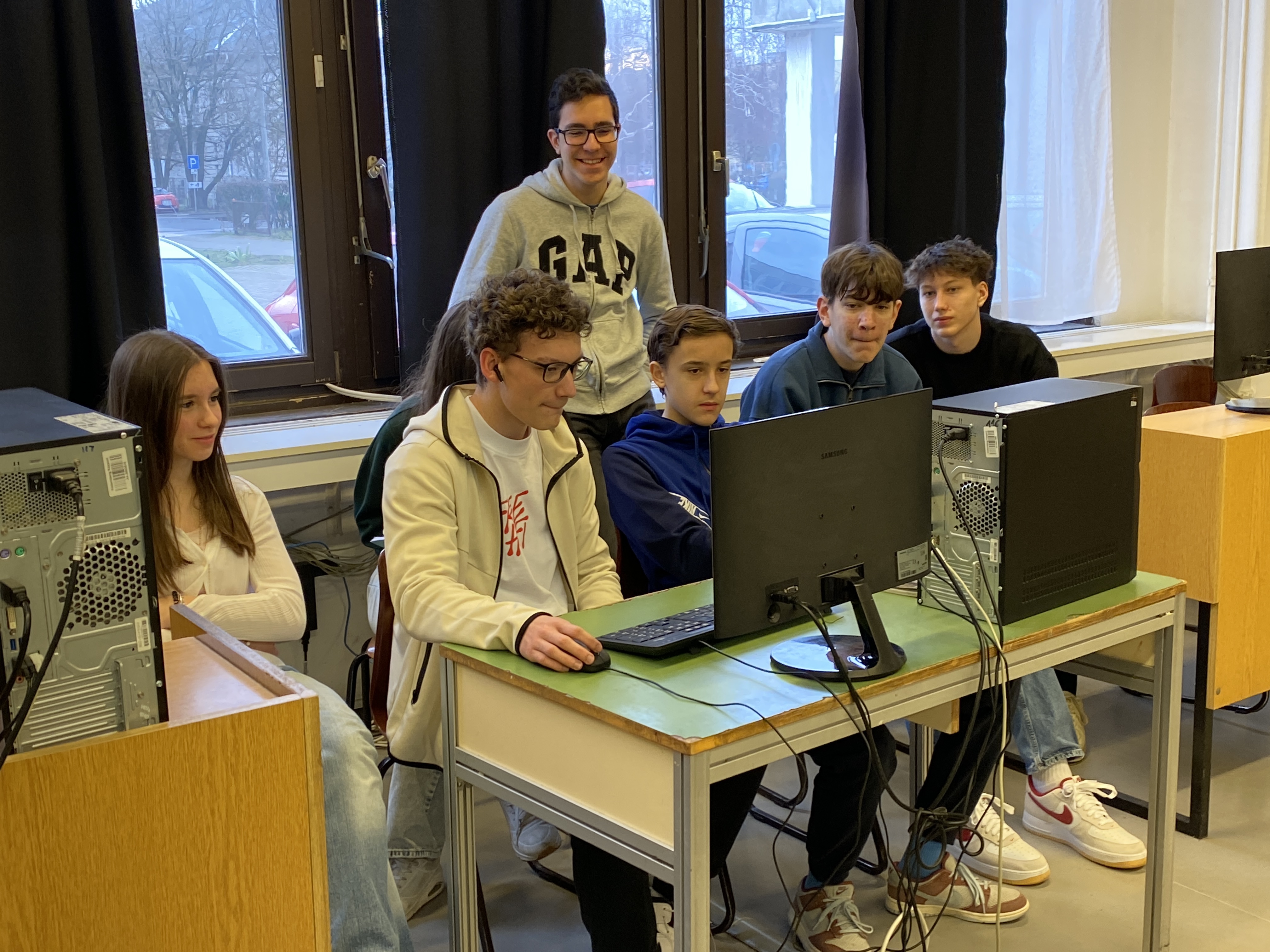 Diákok csoportban dolgoznak a monitor előtt az akadályverseny feladatán