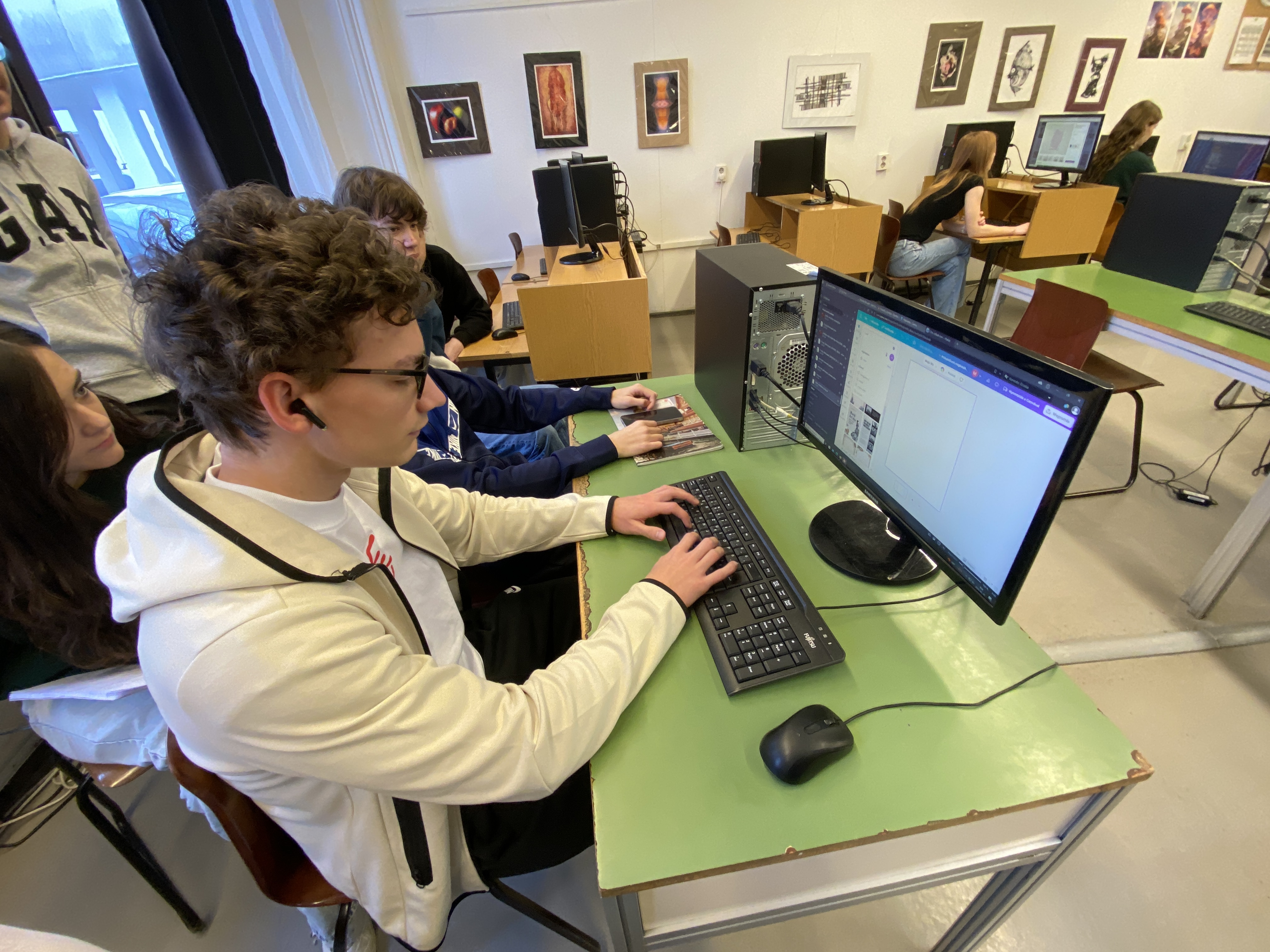 Diák közelről a számítógép előtt, háttérben a számítógépterem